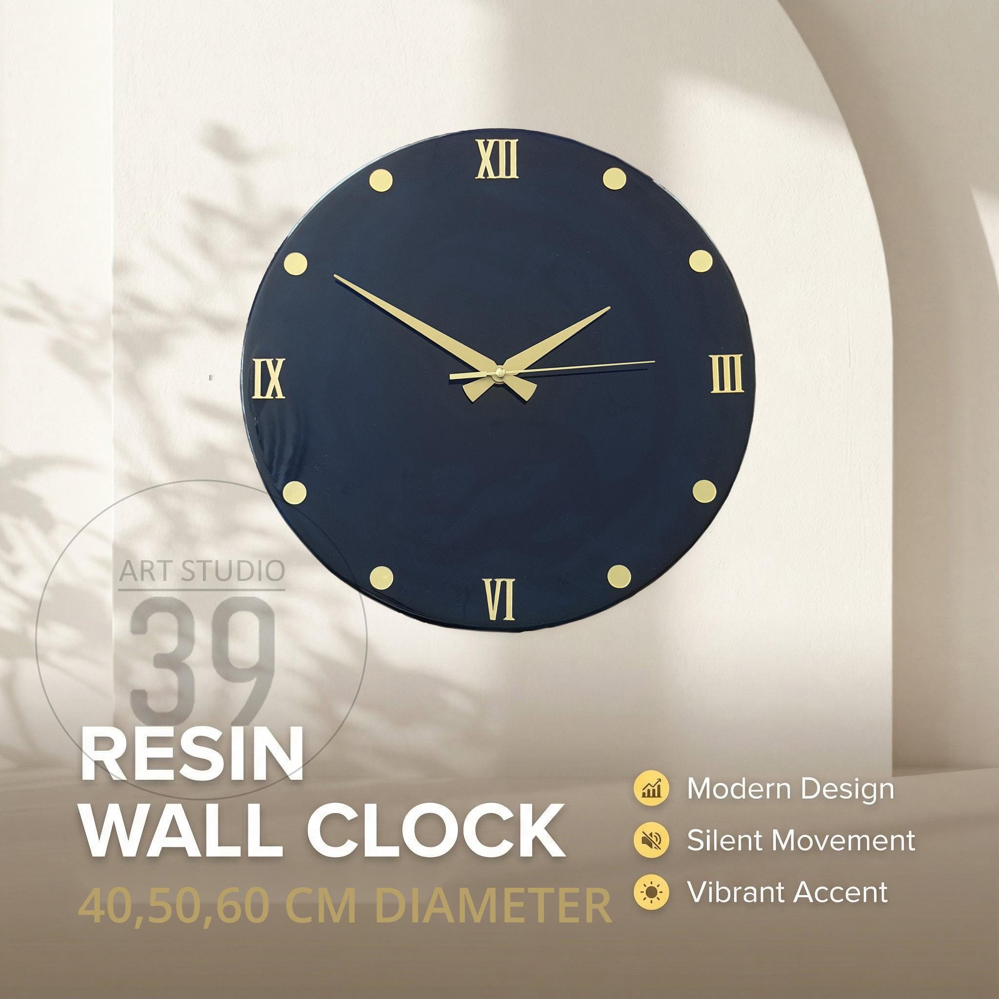 A navy blue resin wall clock with gold-colored hands and hour markers. The clock face features Roman numerals and the text "ART STUDIO 39 RESIN WALL CLOCK 40,50,60 CM DIAMETER". The clock has a modern design and silent movement.