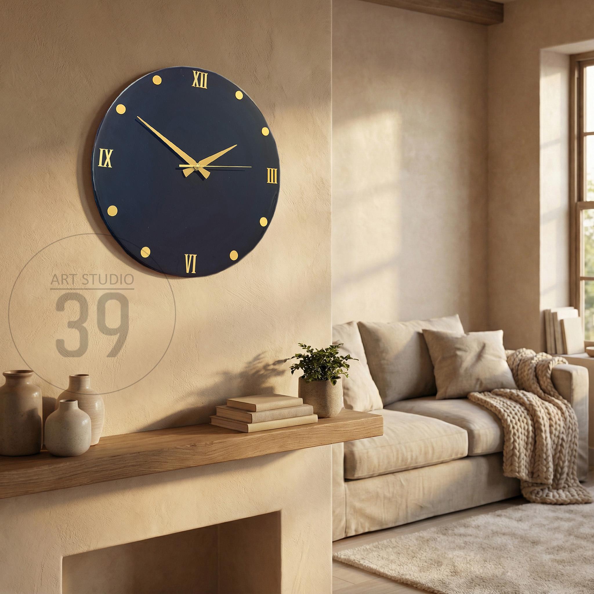 A navy blue wall clock with gold accents, including Roman numerals and dot markers. The clock hands are gold. The image also shows a shelf with vases, books, and a small plant, with the text "ART STUDIO 39".