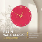 A round, magenta resin wall clock with gold-colored hands and hour markers. The clock face features Roman numerals and is 40 cm in diameter. The text "RESIN WALL CLOCK" is displayed below the clock.