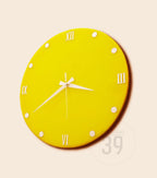 A bright yellow wall clock with white Roman numerals and hands. The clock has a circular shape with white dot markers. The clock hands point to approximately 2:40. The clock is a modern design.