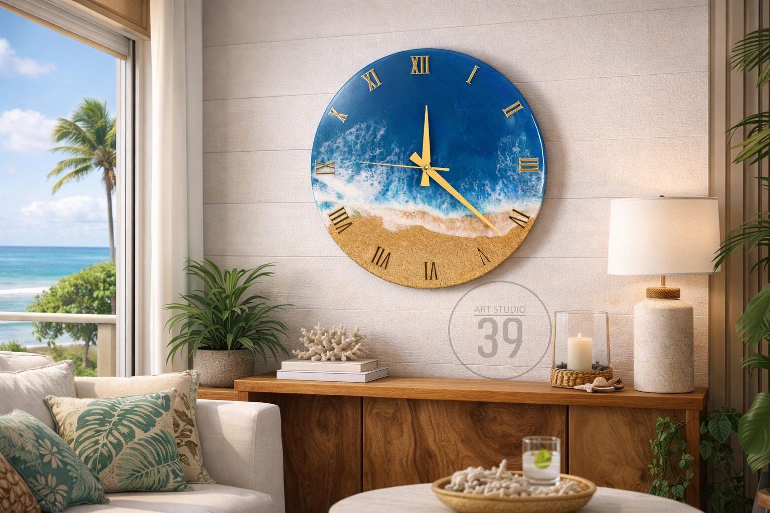 A round wall clock with a beach-themed design. The clock face features a blue ocean, white waves, and a sandy beach. Gold Roman numerals and clock hands complete the design. The clock is mounted on a white wall.