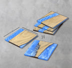 Square wooden coasters with a blue resin river design. Each coaster measures 12 cm (4.7 inches) on each side. The coasters have a natural wood grain and a glossy blue resin finish. The text "39" is visible.