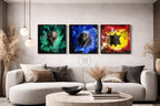 Three square wall art pieces featuring abstract skull designs. Each piece has a different color scheme: green, blue, and red/yellow. The artwork is displayed above a modern sofa in a living room setting.