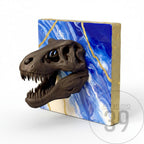 A dark brown dinosaur skull sculpture emerging from a blue and white abstract background with gold accents. The artwork is mounted on a square, gold-edged canvas. The studio logo "Art Studio 39" is visible.
