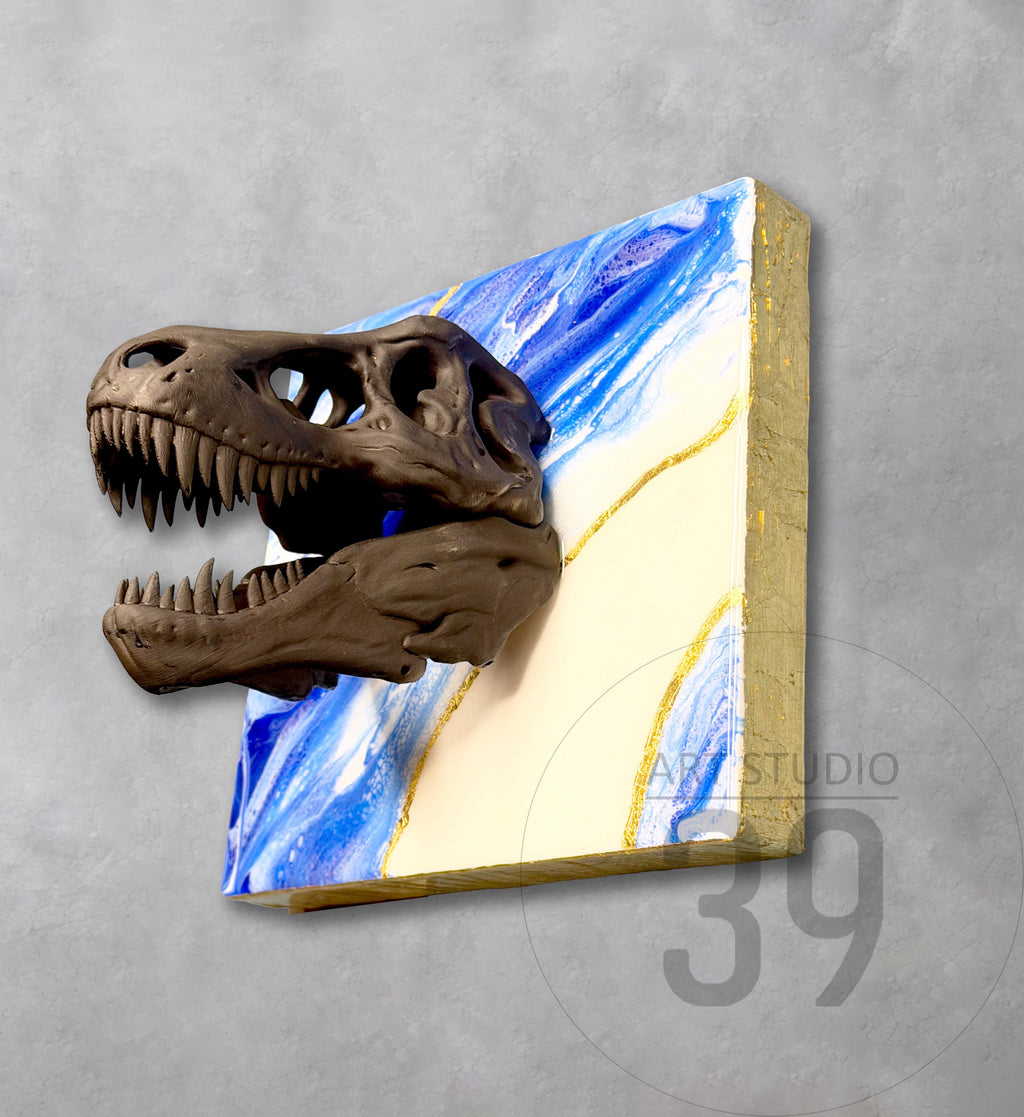 A brown Tyrannosaurus Rex skull sculpture extends from a square canvas. The canvas features a blue and white marbled design with gold accents and a gold-painted edge. The artwork is mounted on a gray wall.