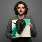 A black triceratops skull sculpture mounted on a square canvas. The canvas features a white and green abstract design with gold accents. The artwork is held against a gray background.