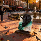 A bronze Triceratops head sculpture mounted on a marble-like surface with green and gold accents. The sculpture is displayed outdoors in a park setting, with the text "ART STUDIO 39" visible.