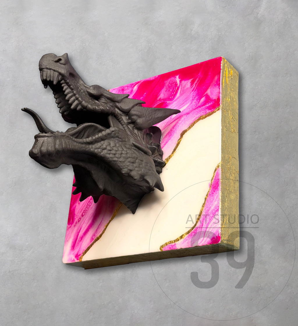 A dark gray dragon head sculpture emerging from a square canvas. The canvas features a pink and white abstract design with gold accents and a gold border. The text "ART STUDIO 39" is visible.