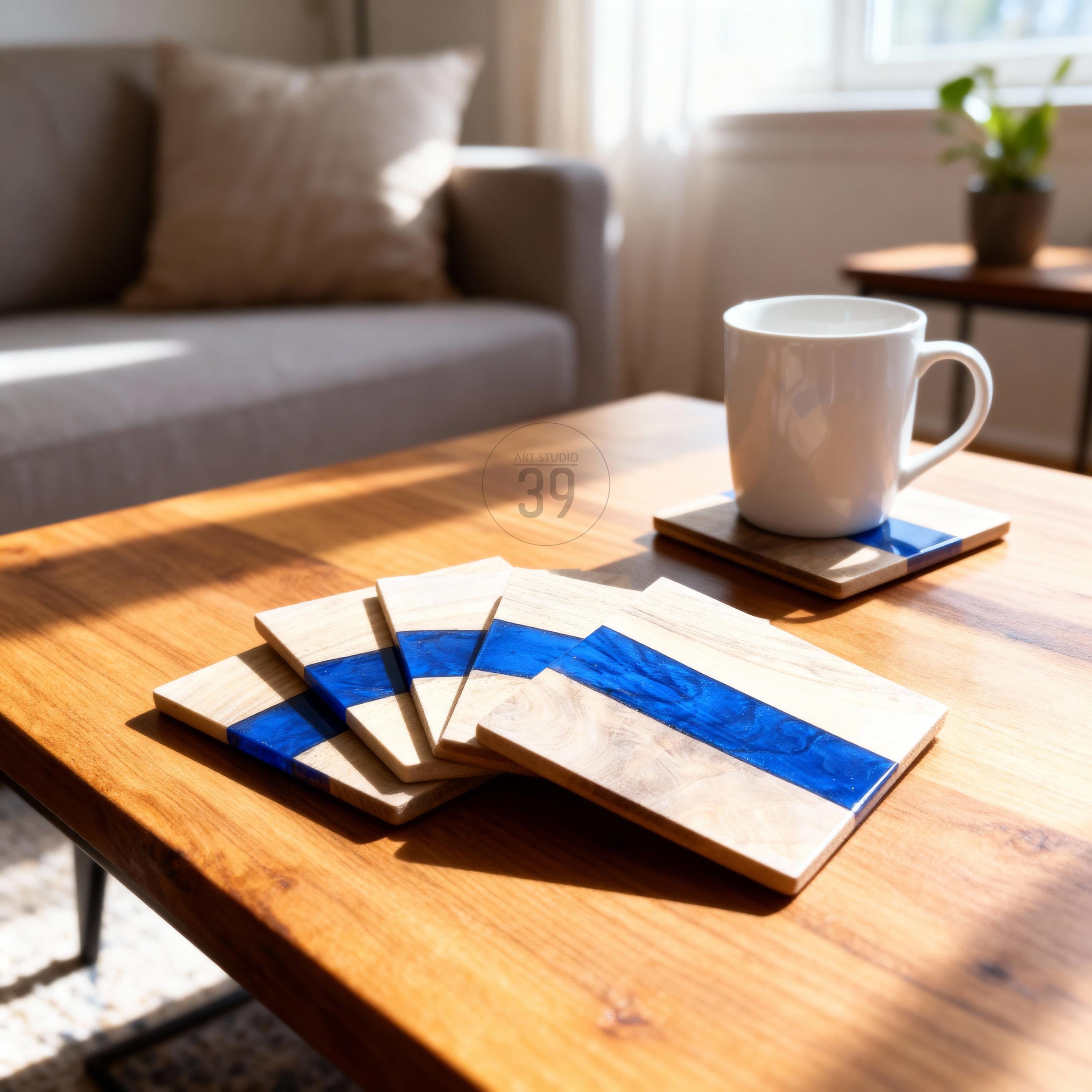Wooden coasters with a blue resin stripe. A white mug sits on one coaster, with others stacked nearby. The coasters are on a wooden table, with a couch and plant in the background. The coasters have the number "39" on them.