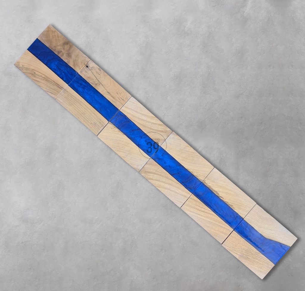 Wooden decorative piece with a vibrant blue resin river running through the center. The wood is light-colored, and the resin is a deep blue. The number "39" is visible on the wood. The piece is made of several rectangular blocks.