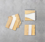 Square wooden coasters with a white resin stripe. Each coaster is 12 cm by 12 cm. The coasters have a natural wood grain pattern. The image includes a stack of coasters and individual coasters.