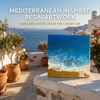 Mediterranean-inspired resin artwork depicting a coastal scene with blue ocean, white waves, and a sandy beach. Available sizes: 25x25 cm and 30x30 cm. The artwork is displayed outdoors with potted plants and a scenic background.