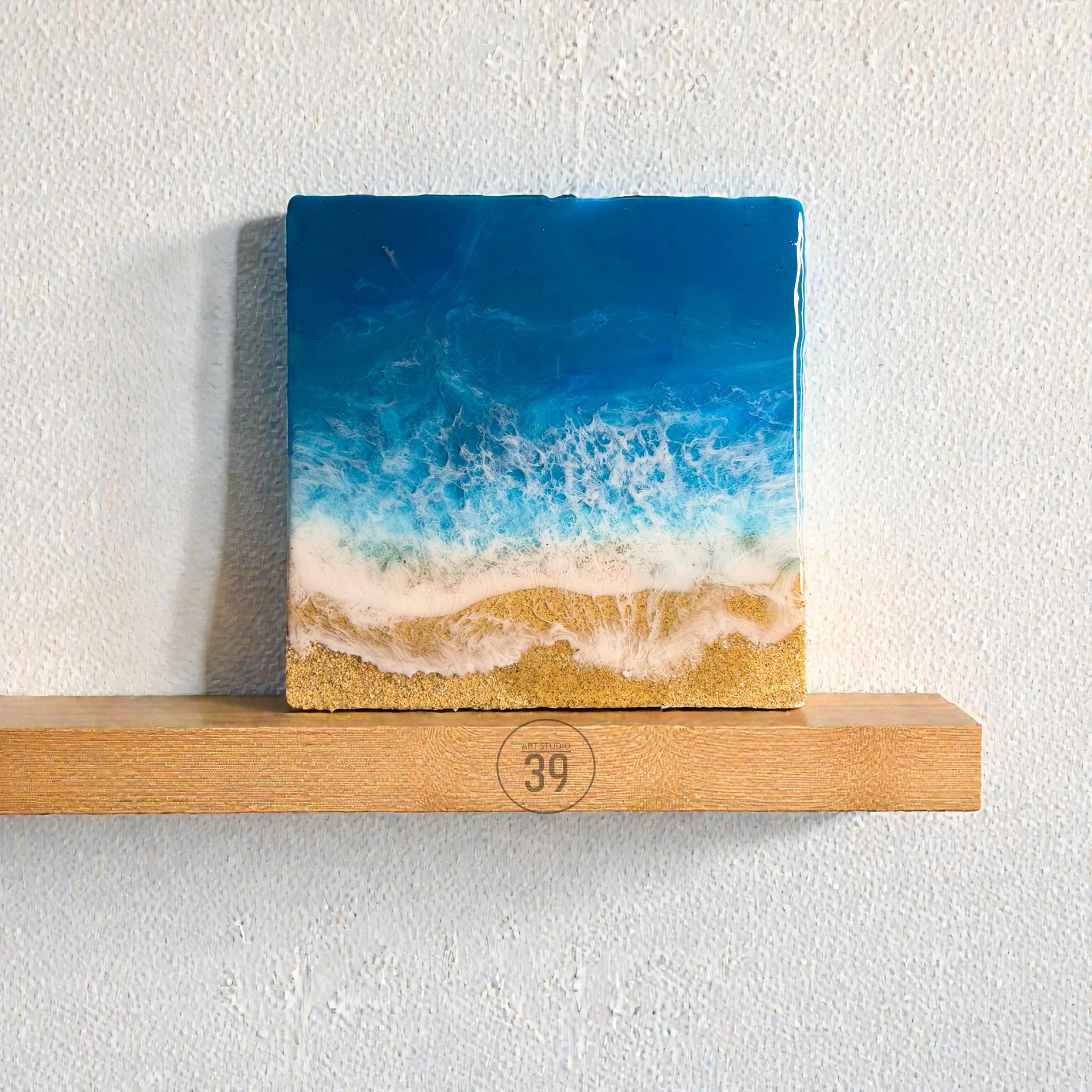 Square resin art piece depicting an ocean scene. The artwork features a gradient of deep blue to white, representing the sea and foamy waves. The bottom shows a sandy beach. The number "39" is visible.