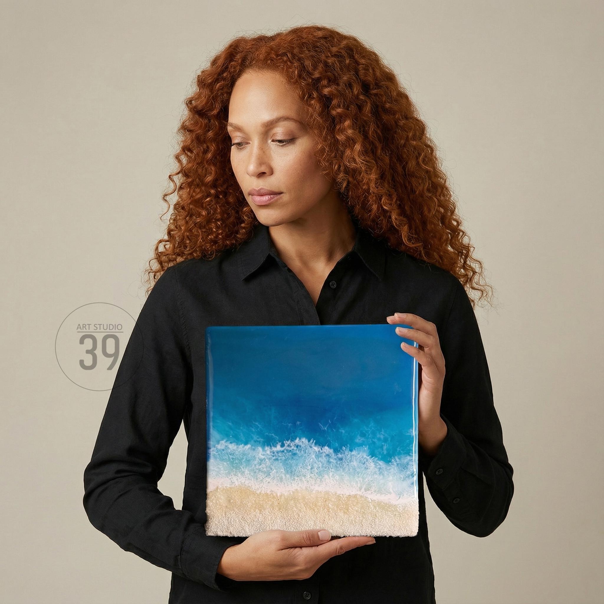 Square artwork depicting an ocean scene with a sandy beach. The artwork features shades of blue and white to represent the ocean and waves, and a tan color for the sand. The text "ART STUDIO 39" is in the upper left corner.