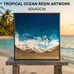 Square resin artwork depicting a tropical ocean scene. The artwork features a dark blue ocean, white foamy waves, and a golden sand beach. The framed piece measures 40x40cm.