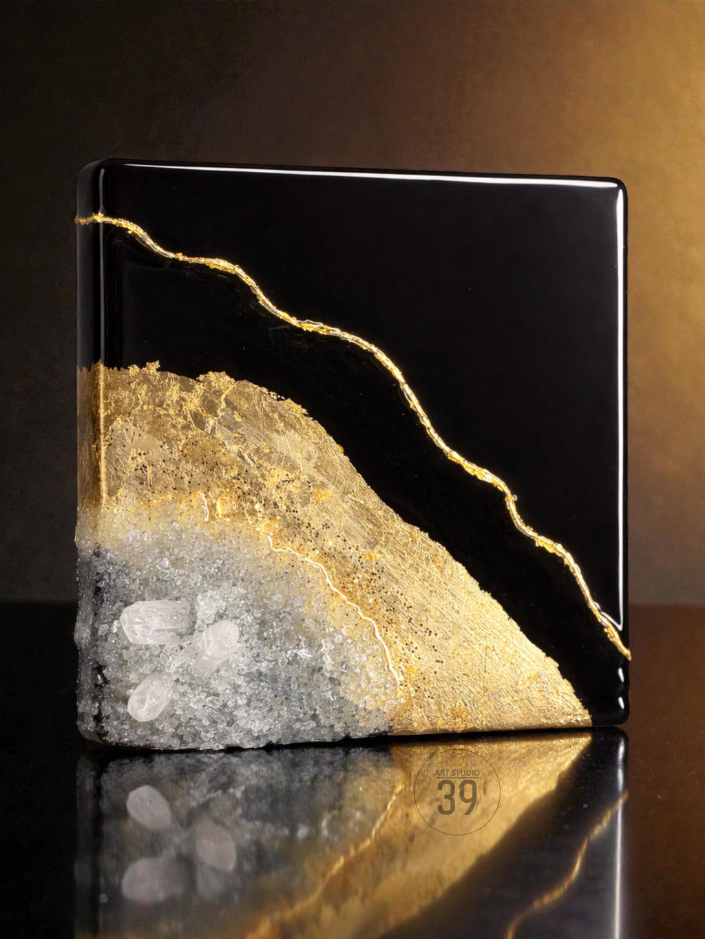 A square, black decorative object with a gold-colored, vein-like design. The bottom half features a textured, light gray and gold surface with embedded clear crystals. The object has a glossy finish.