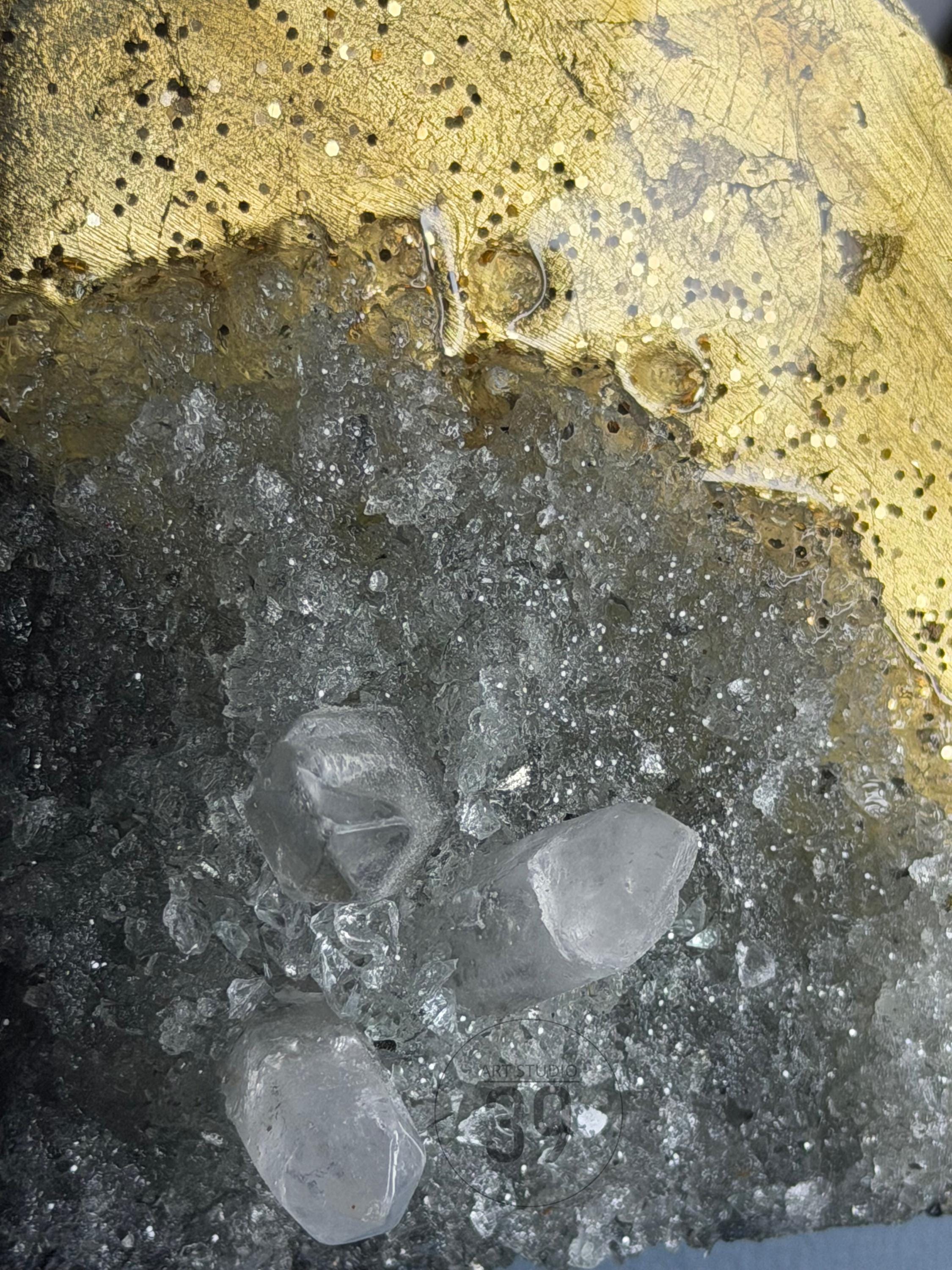 Close-up of a decorative art piece featuring a gold-colored, glitter-covered top section and a lower section with clear, crystalline formations. The piece has a textured appearance with a mix of reflective and opaque elements.