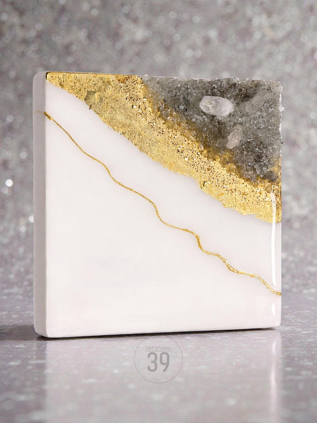 Square white resin art piece with gold leaf and a gold line accent. The top right corner features a gray, textured section with clear crystal accents. The bottom right corner has the text "ART STUDIO 39".