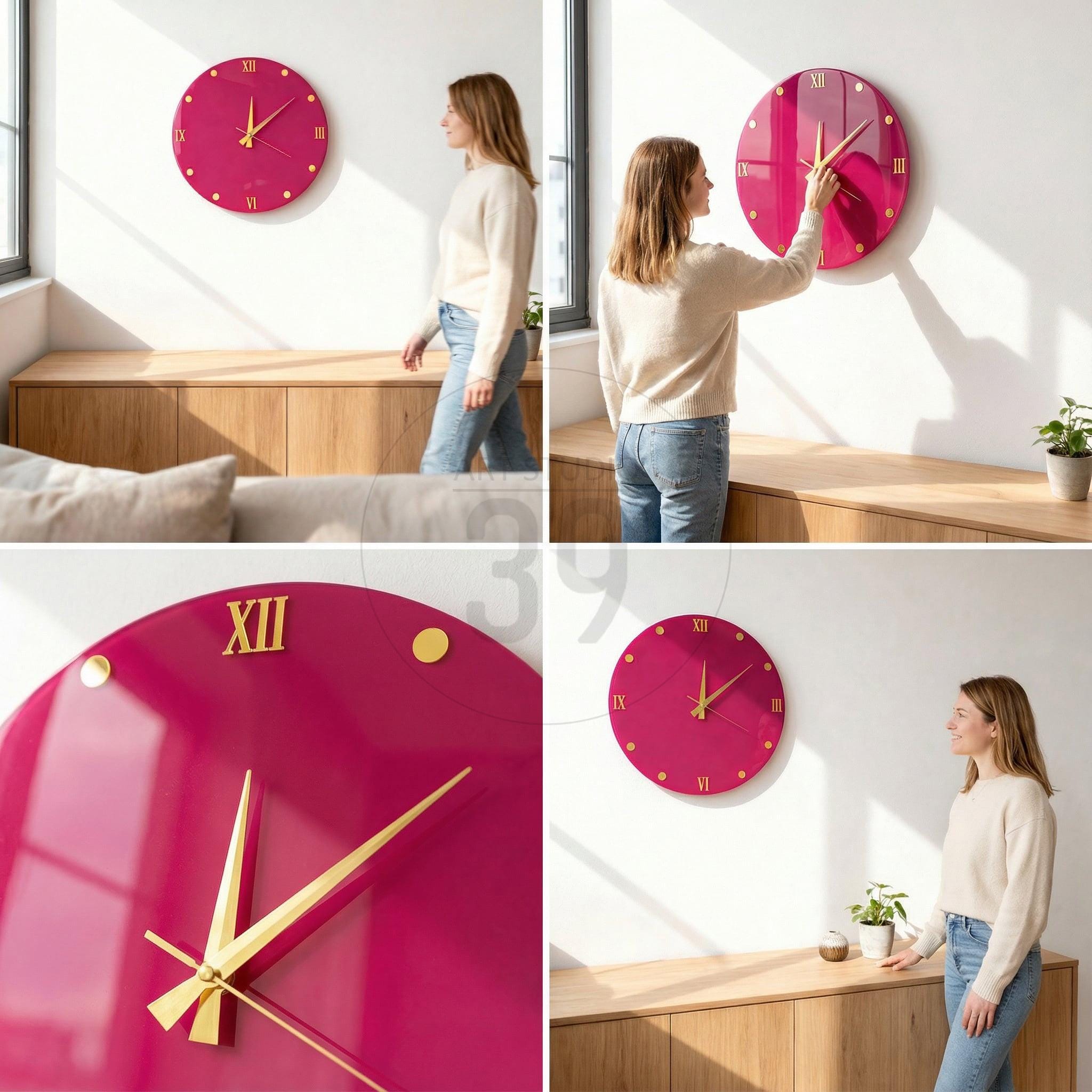 A round, magenta wall clock with gold-colored hands and hour markers. The clock has a glossy finish and features Roman numerals at the top and bottom. The clock is mounted on a white wall.