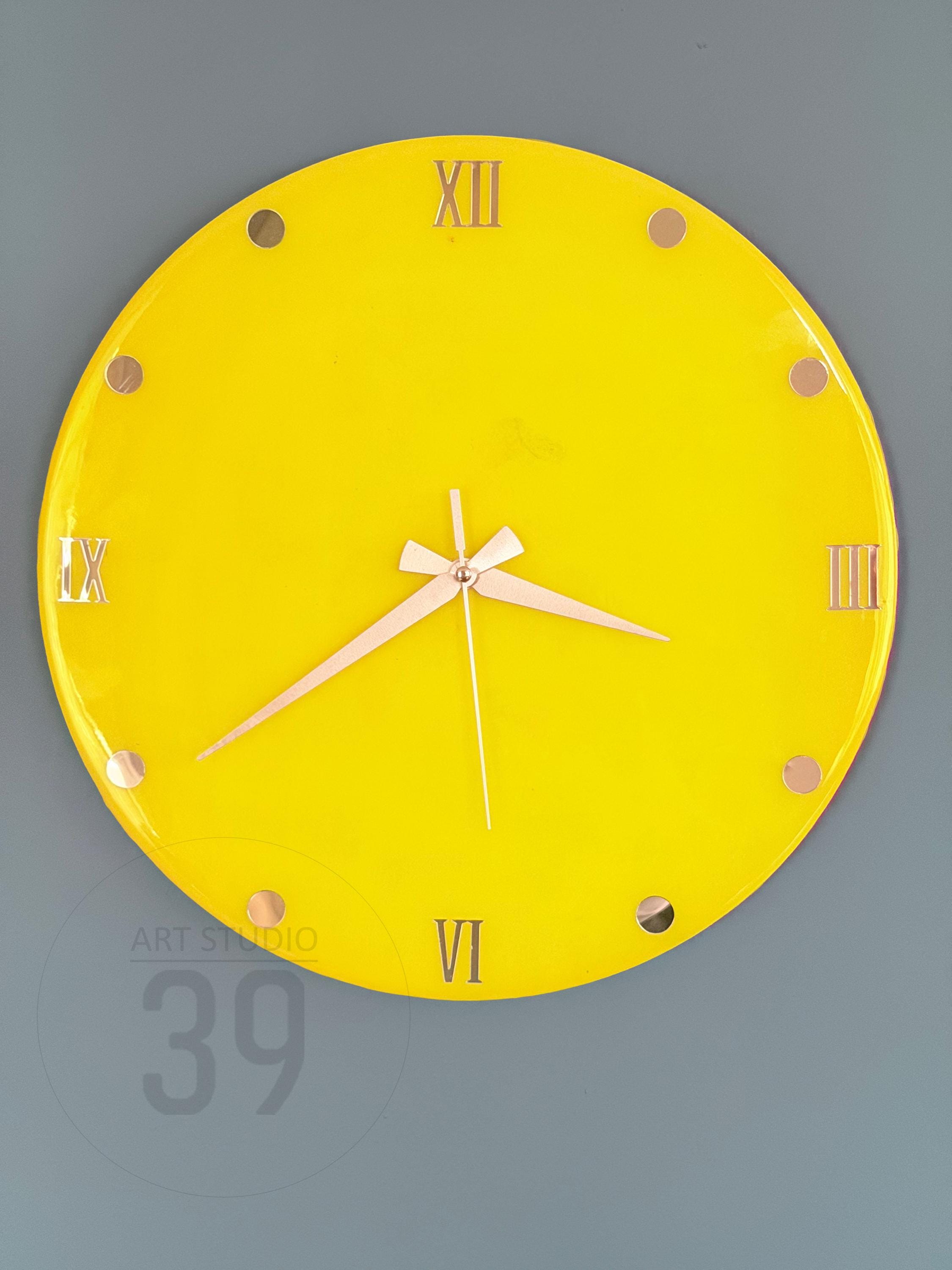 A round, bright yellow wall clock with gold-colored Roman numerals and hands. The clock face has gold-colored dots marking the hours. The clock reads 6:10. The text "ART STUDIO 39" is visible on the bottom left.