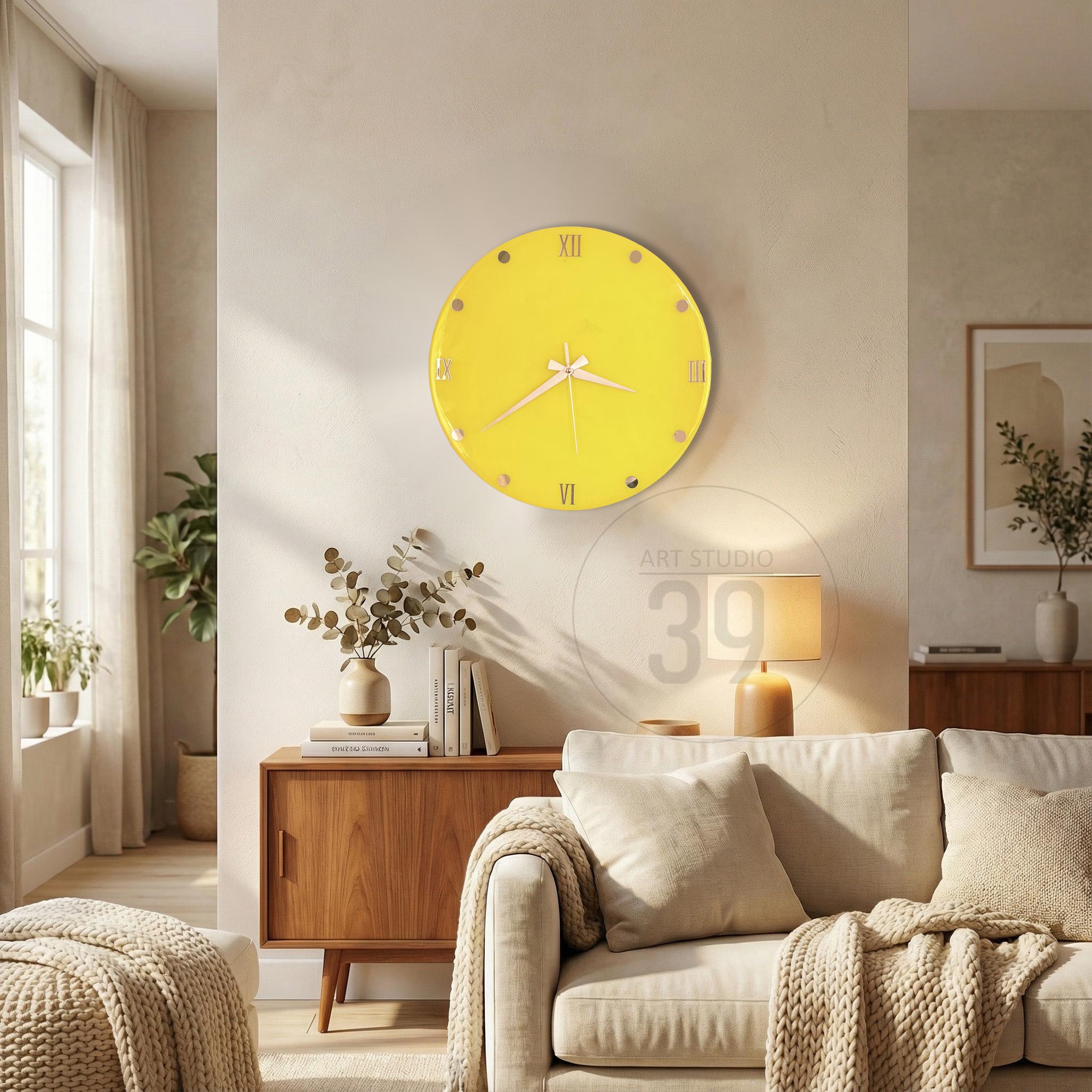 A round, yellow wall clock with Roman numerals and white hands. The clock is mounted on a light-colored wall. The clock is a decorative element in a living room setting.