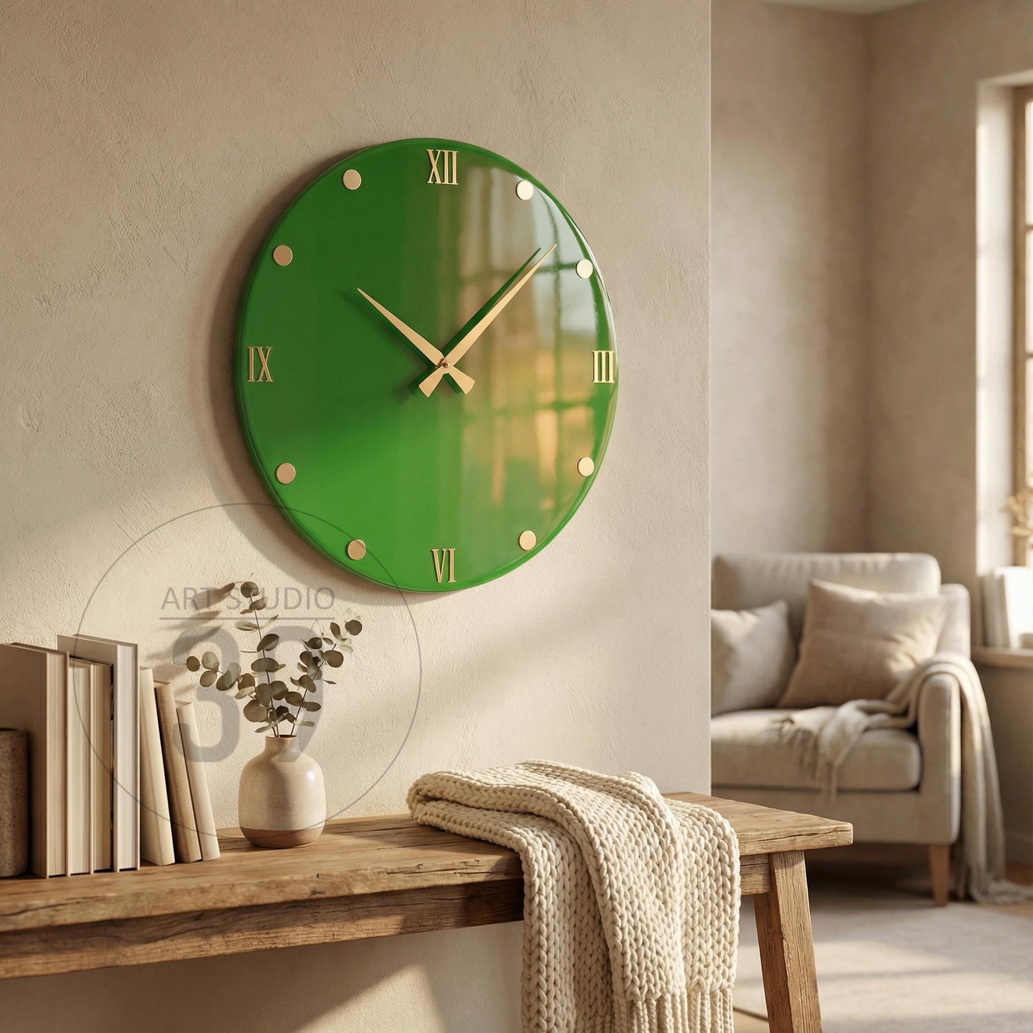 A round, green wall clock with gold-colored hands and hour markers. The clock features Roman numerals and is mounted on a neutral-colored wall. The clock is a decorative piece for home decor.