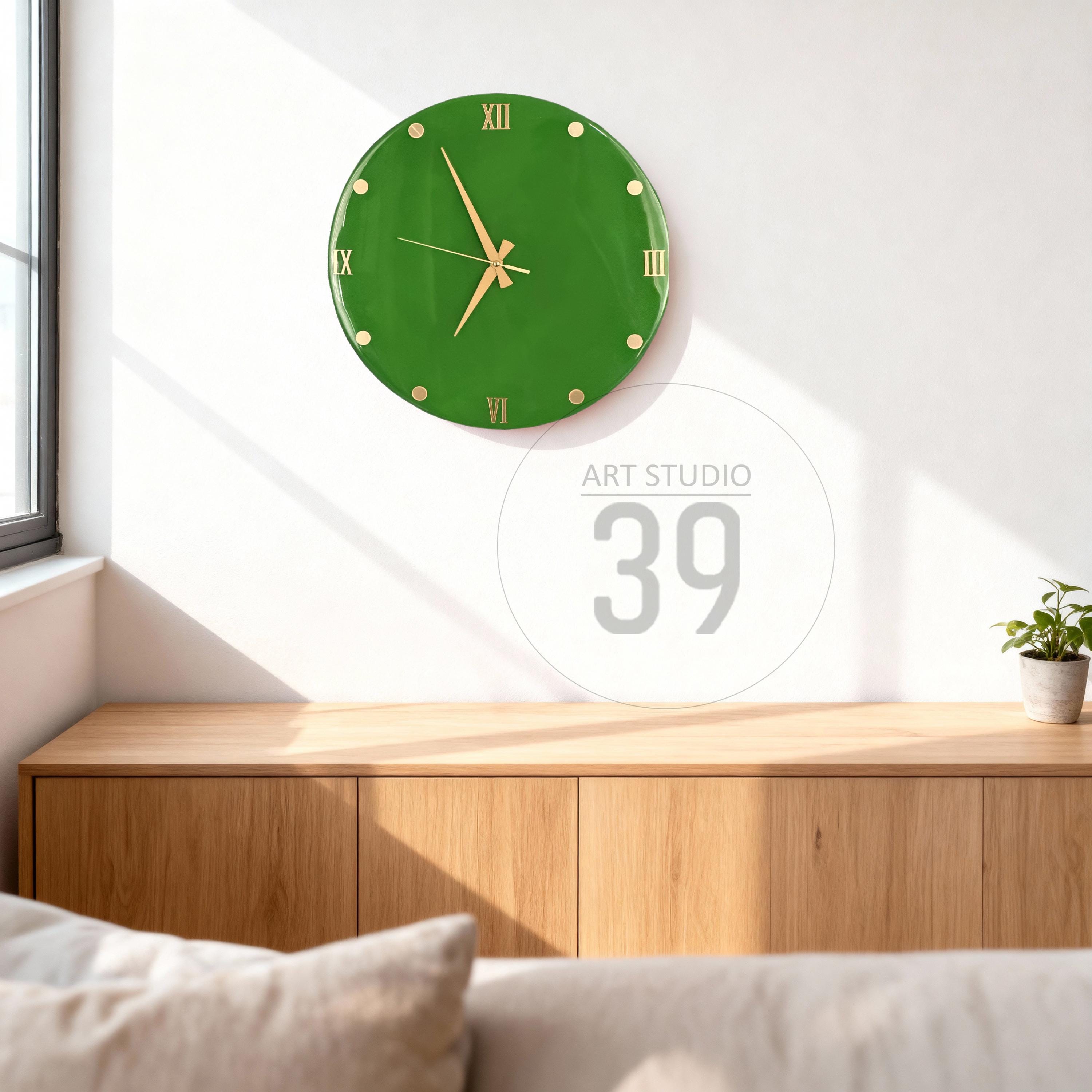 A green wall clock with gold-colored hands and Roman numerals. The clock is round and mounted on a white wall. The text "ART STUDIO 39" is in a circle below the clock.