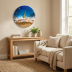 A round wall clock with a beach scene design. The clock face features a blue and white ocean design with gold Roman numerals and hands. The clock is hanging on a beige wall above a wooden console table.