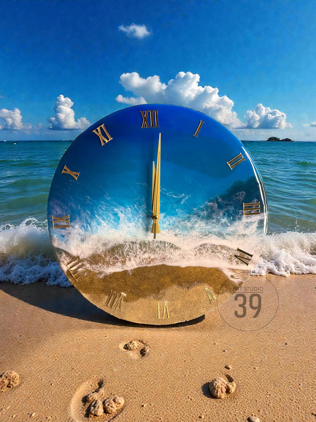 A round wall clock with a beach scene design. The clock face features a blue ocean and sandy beach, with gold Roman numerals and clock hands. The clock is set on a sandy beach with ocean waves and a blue sky.