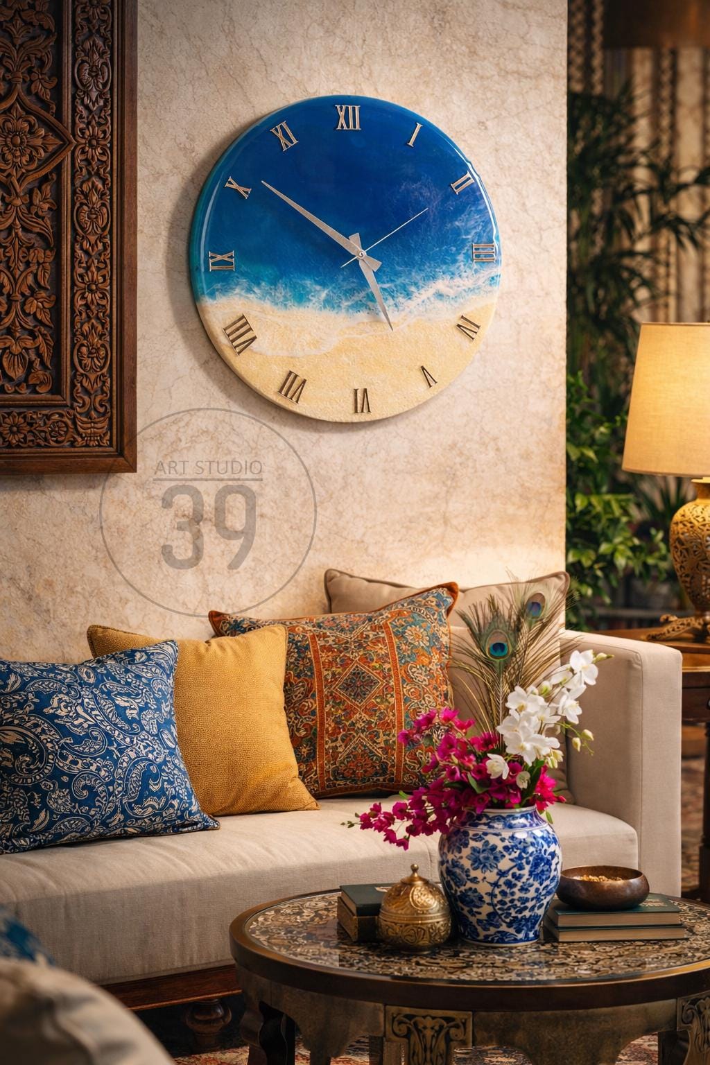 A round wall clock with a blue and white ocean-themed design. The clock face features Roman numerals and silver hands. The clock is mounted on a beige wall above a sofa with decorative pillows. The room is decorated with a lamp and a coffee table.