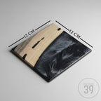 Square wooden serving board, 12 cm x 12 cm, with a light wood grain finish on one side and a black resin design on the other. The board has a dark border and is from Art Studio 39.