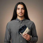 A stack of square coasters with a black and white marbled design. The coasters have a natural wood edge. The person in the image is wearing a gray button-down shirt.