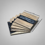 A stack of six square coasters, each measuring 12 cm. The coasters feature a light wood grain design with a dark blue and gray resin river. The coasters are from the "ART STUDIO" brand.