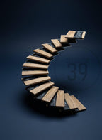 A modern, curved staircase with wooden steps and black accents. The steps are made of light-colored wood and are set against a dark blue background. The text "ART STUDIO 39" is visible in the background.