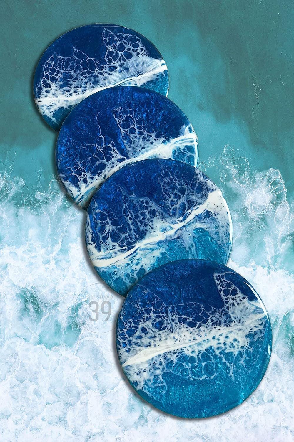 Four round coasters with a blue and white ocean wave design. The coasters are arranged in a diagonal row, with the top coaster partially visible. The coasters have a glossy finish and are made of resin. The text "ART STUDIO 39" is visible on the bottom coaster.