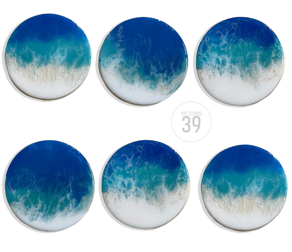 Six round coasters with a resin ocean wave design. The coasters feature shades of blue, teal, and white, with a glossy finish. The text "ART STUDIO 39" is in the center.