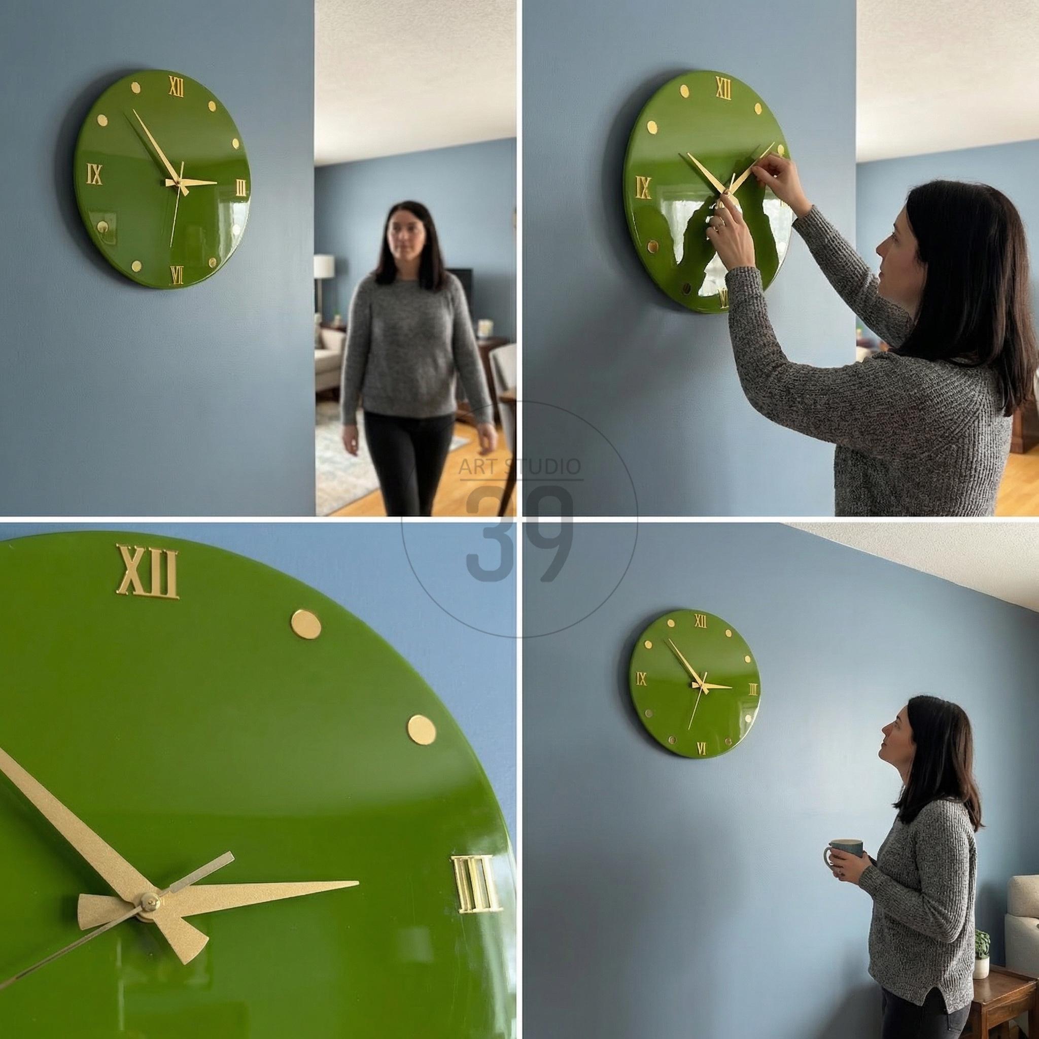 A round, green wall clock with gold-colored Roman numerals and hands. The clock is mounted on a blue wall. The clock's face is a solid, glossy green color. The clock is a decorative item for home decor.