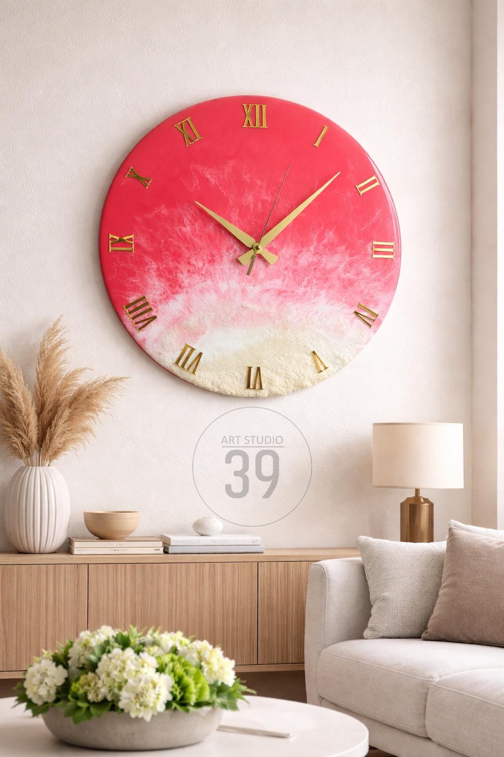 A large, round wall clock with a red and white resin design. The clock features gold-colored Roman numerals and hands. The text "ART STUDIO 39" is visible.