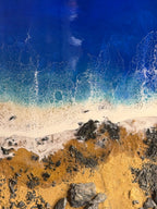 Abstract artwork depicting a beach scene. The top portion shows a deep blue ocean with white foamy waves. The bottom features golden sand, dark rocks, and a hint of white foam where the waves meet the shore. The number "39" is visible.