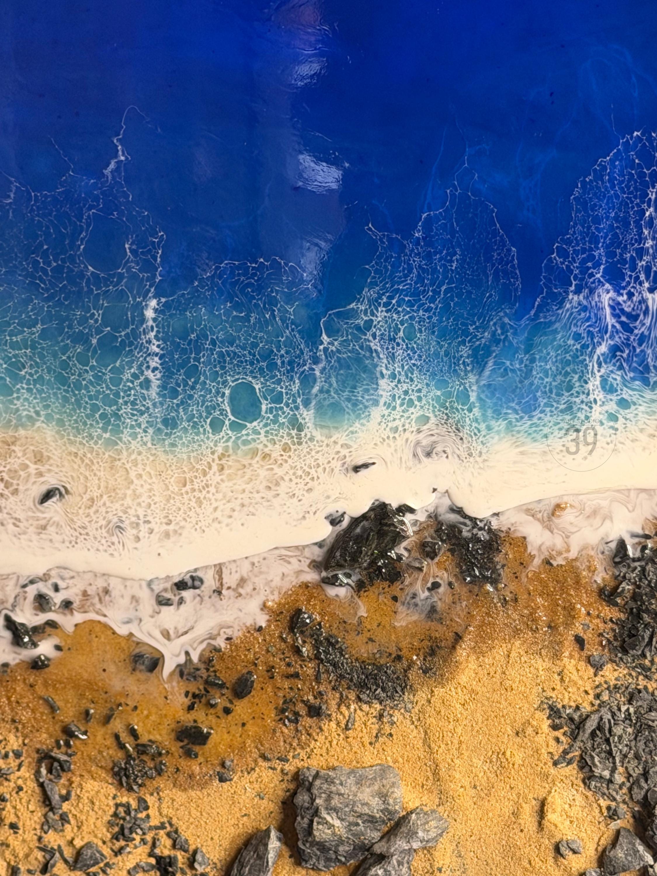 Abstract artwork depicting a beach scene. The top portion shows a deep blue ocean with white foamy waves. The bottom features golden sand, dark rocks, and a hint of white foam where the waves meet the shore. The number "39" is visible.
