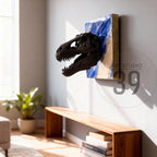 A dark brown Tyrannosaurus Rex skull sculpture emerging from a blue and beige painted square. The artwork is mounted on a light gray wall, with the text "ART STUDIO 39" in a circle on the wall.