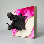 A black dragon head sculpture emerging from a square canvas. The canvas features a pink and white marbled design with gold accents. The side of the canvas is a muted green color. The text "ART STUDIO 39" is visible.