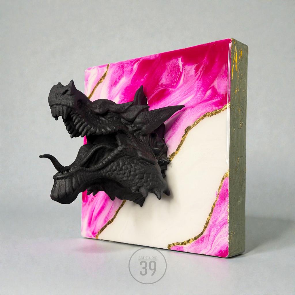A black dragon head sculpture emerging from a square canvas. The canvas features a pink and white marbled design with gold accents. The side of the canvas is a muted green color. The text "ART STUDIO 39" is visible.