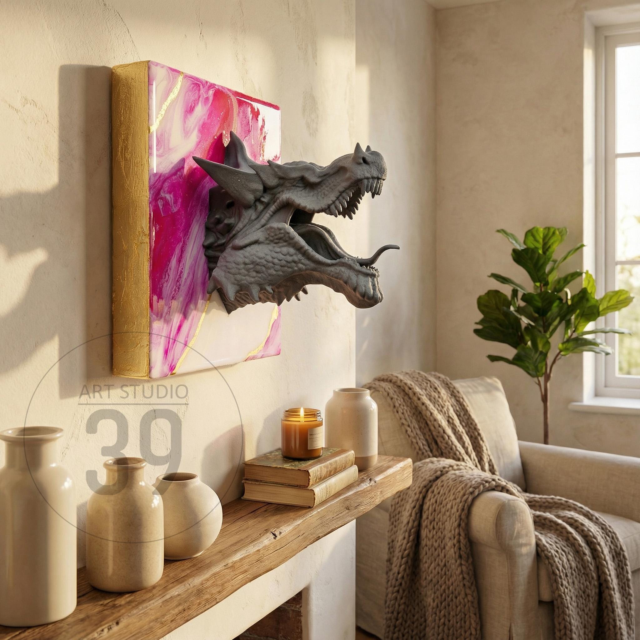A gray dragon head sculpture emerging from a pink and gold abstract painting. The artwork is mounted on a wall, with the text "ART STUDIO 39" visible. The scene includes a wooden shelf with vases and a candle.