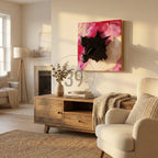 A black dragon head sculpture mounted on a square canvas with a pink and white abstract background and gold accents. The artwork is displayed in a living room setting, above a wooden cabinet.