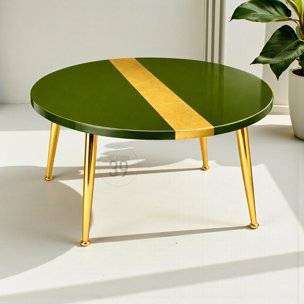 A round coffee table with a glossy green surface and a gold stripe. The table has four gold-colored, angled legs. The table is a modern design.