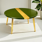 A round coffee table with a glossy green surface and a gold stripe. The table has four gold-colored, angled legs. The table is a modern design.