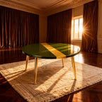 A round coffee table with a glossy green surface and a gold stripe down the center. The table has gold-colored legs and sits on a cream-colored rug. The room has brown curtains and a window with sunlight.