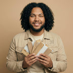 A person holding a fan of wood and white samples. The samples are various shades of brown and white. The person is wearing a tan jacket and a light-colored shirt. The number "39" is printed on the jacket.