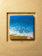 Square resin art piece depicting an ocean scene with blue and white waves crashing onto a golden sand beach. The artwork is set within a textured, light brown frame. The number "39" is in a circle at the bottom.
